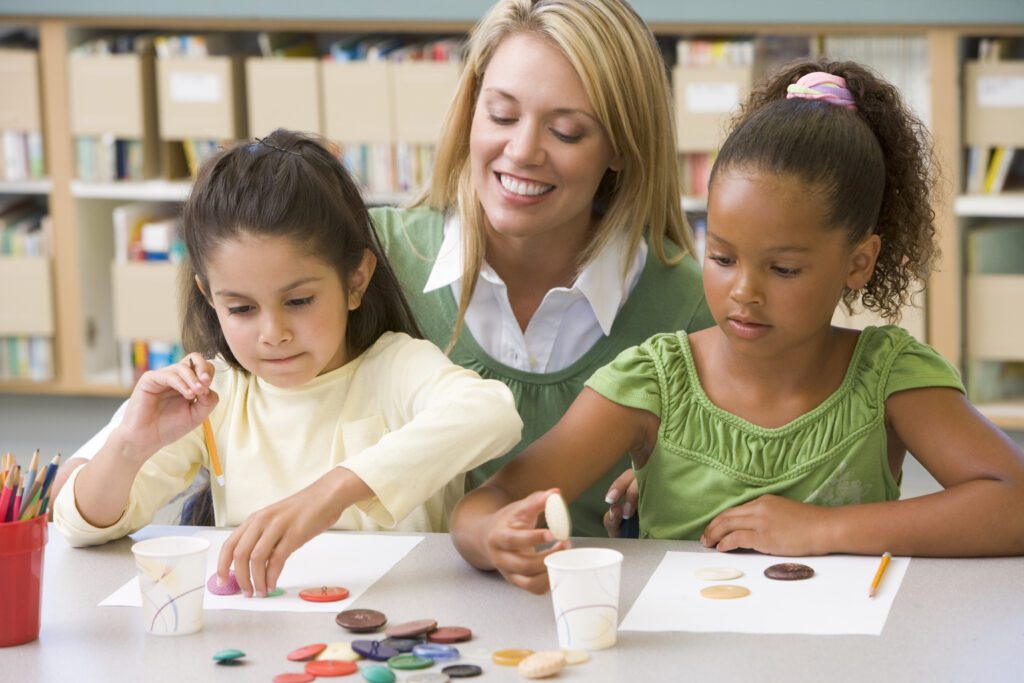 Kindergarten teacher sitting with students and smiling in art class